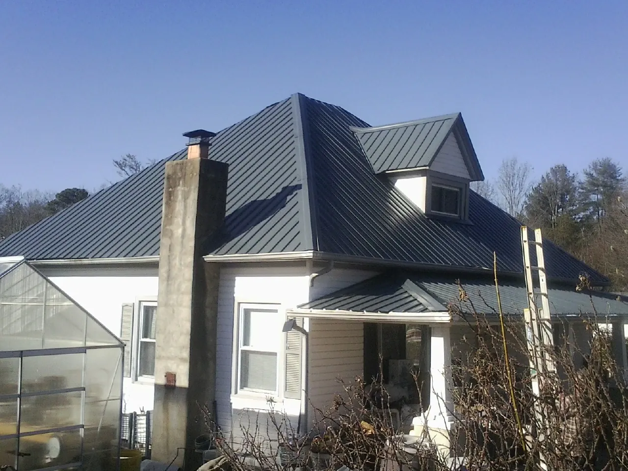 Dark blue standing seam metal roof on a white farmhouse with dormer — Slate & Tile Roof Repair by Roofing Brothers in South Walpole