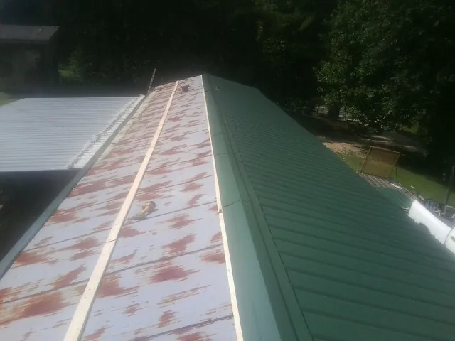 Old rusted panels beside newly installed green metal roofing — Wind Damage Roof Repair by Roofing Brothers in South Walpole