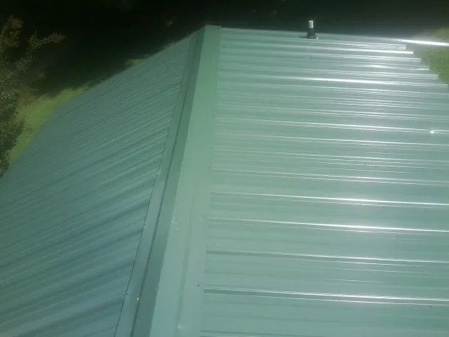 New green metal panels meeting at the ridge of a roof in South Walpole