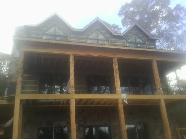 Dormers and porch framing on a large log home under construction — Roof Coating work by our crew in South Walpole