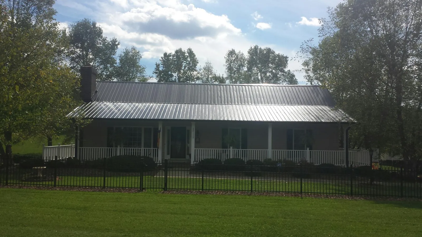 Gray metal roof on a brick ranch with a full width front porch — Gutter Guard Installation work by our crew in South Walpole