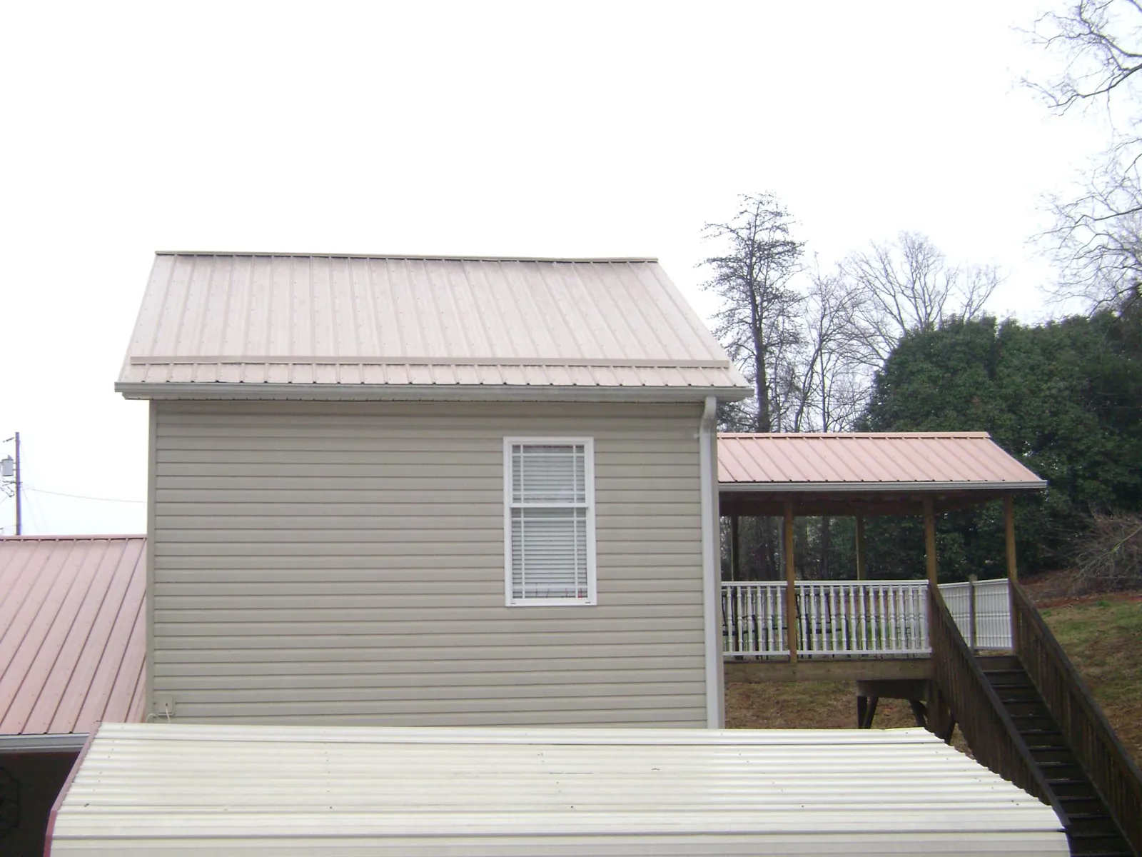 Tan metal roofs on a two story addition and attached porch, from a Roof Replacement job in South Walpole
