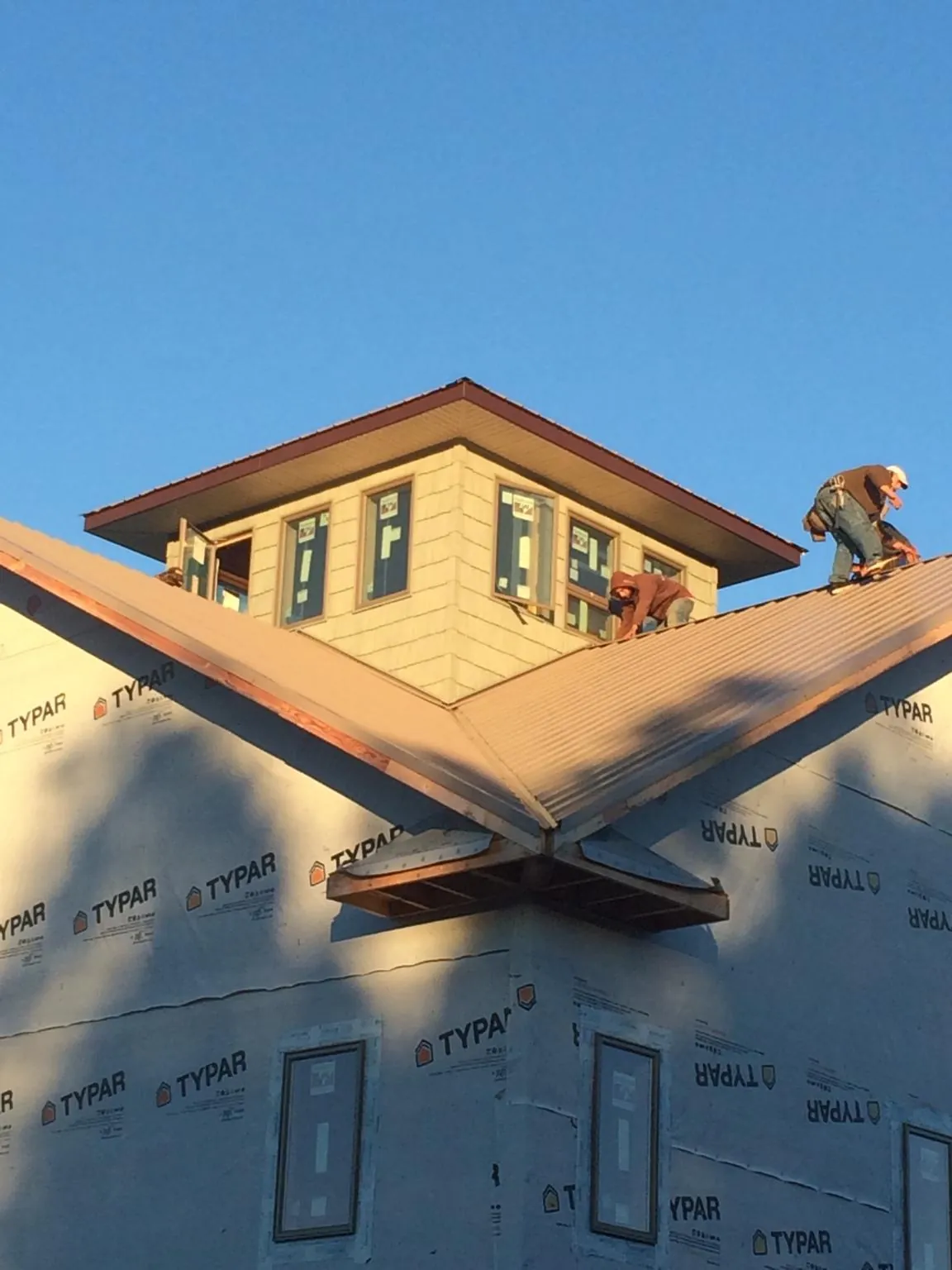 Roofers working around a rooftop cupola on a new metal roof at sunset — Roof Waterproofing in South Walpole by Roofing Brothers